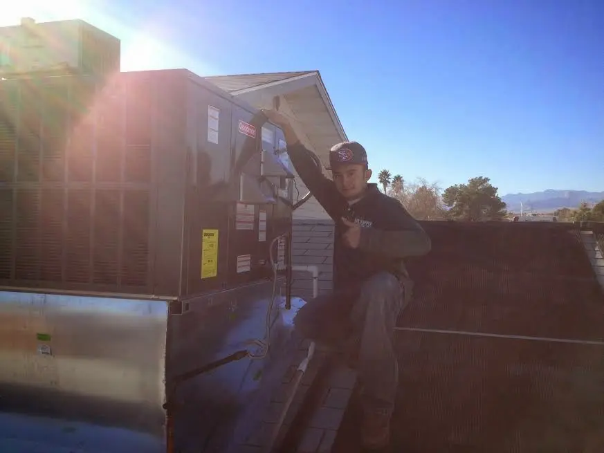 HVAC technician performing Air Duct Repair on a rooftop unit in Adel